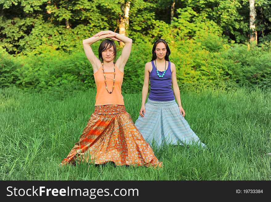 Two girls do yoga in the forest