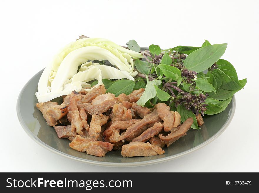 Thai style grilled pork on disk with cabbage and sweet basil