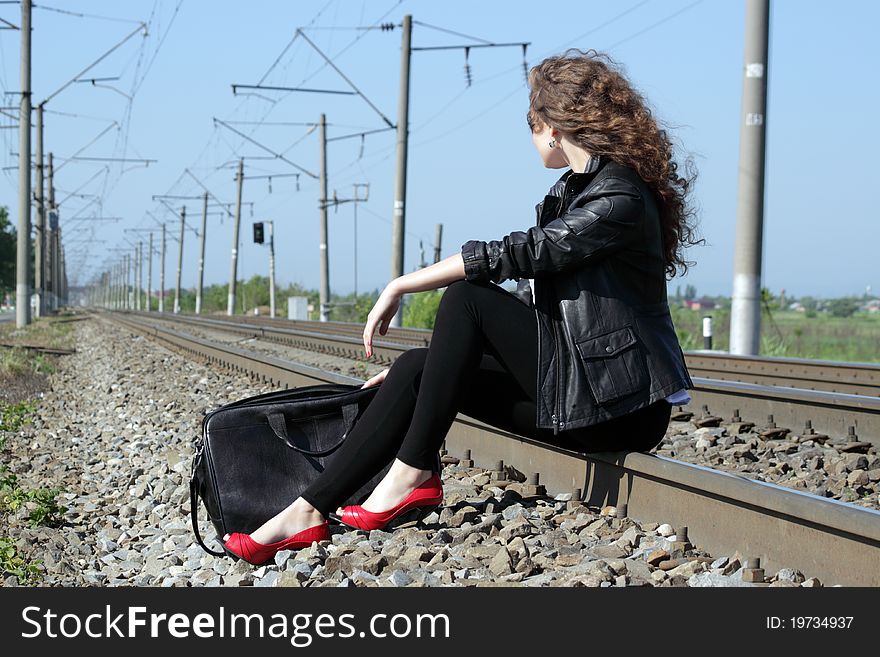 A girl sits on the rail waiting for the train. A girl sits on the rail waiting for the train