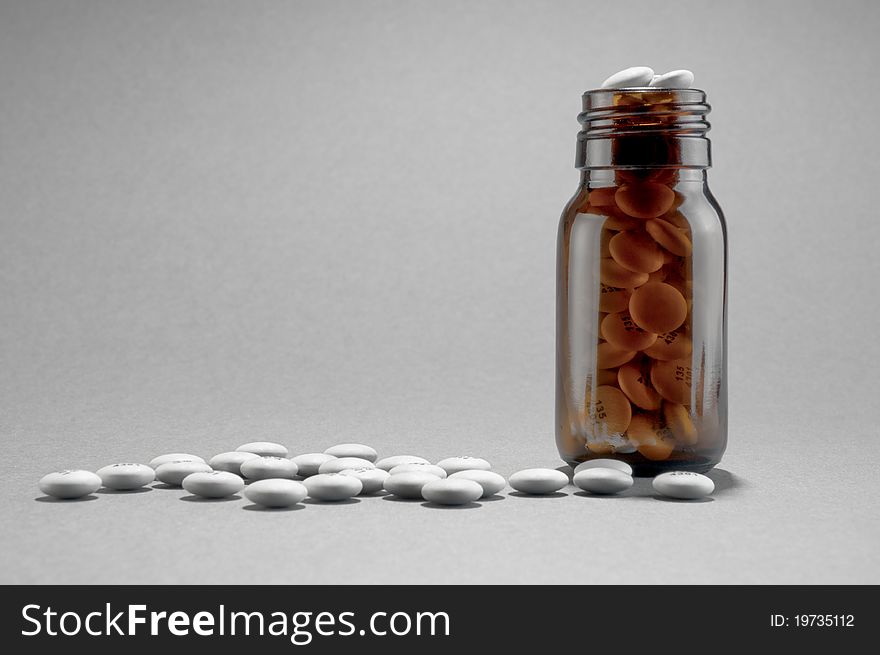 Bottle of white pills/tablets on plain backround with space for text