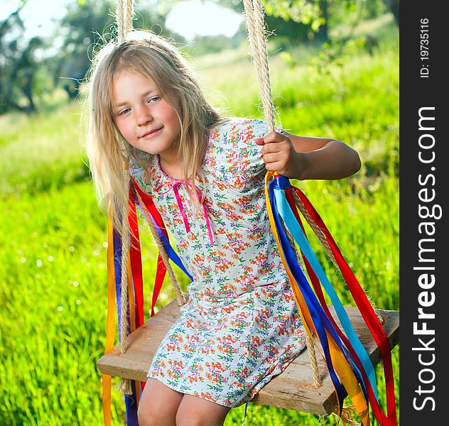 Young cute girl on swing with ribbons in the garden. Young cute girl on swing with ribbons in the garden