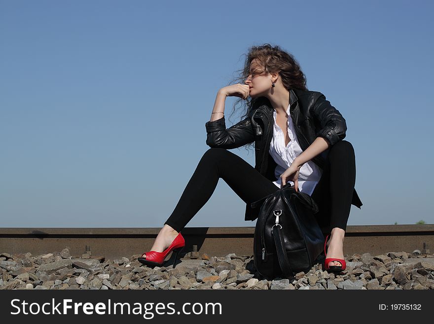 A girl sits on the rail waiting for the train. A girl sits on the rail waiting for the train