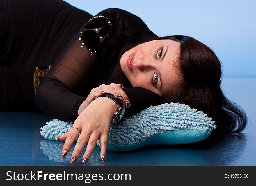 Beautiful woman lying on pillows on blue background