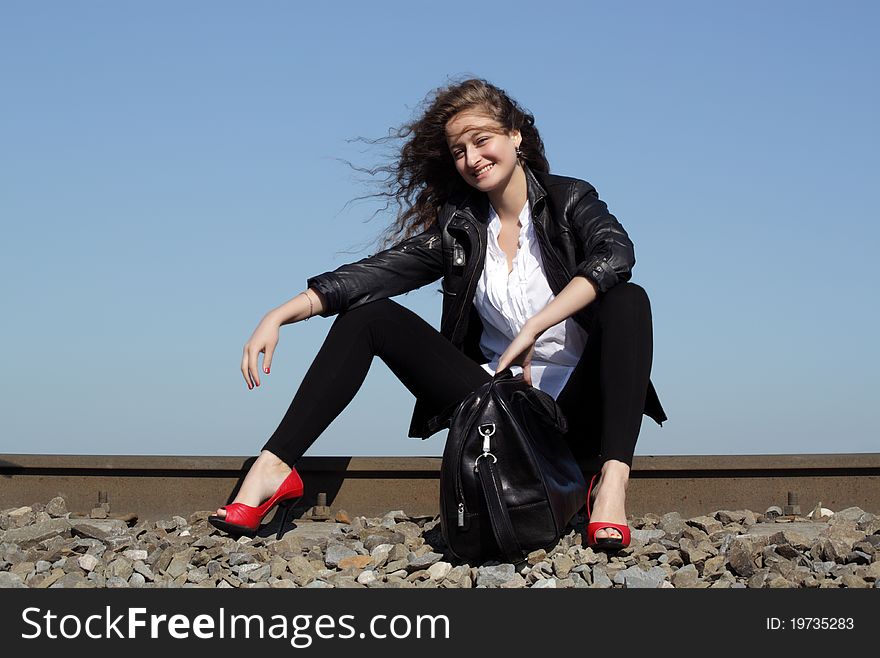 A girl sits on the rail waiting for the train. A girl sits on the rail waiting for the train