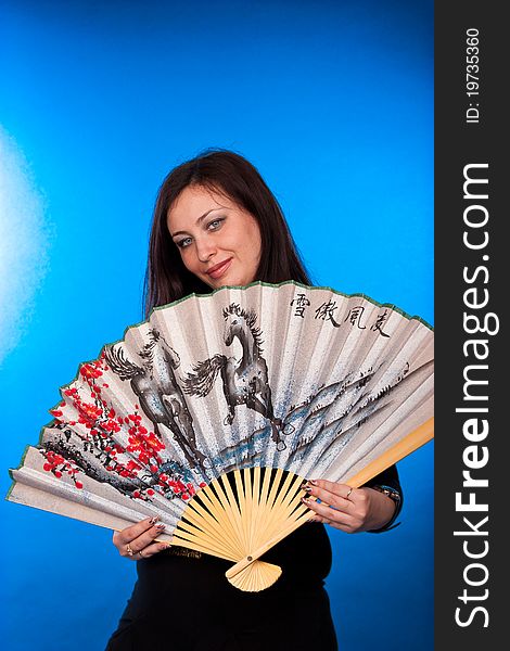 Portrait of a beautiful woman with fantail on blue background