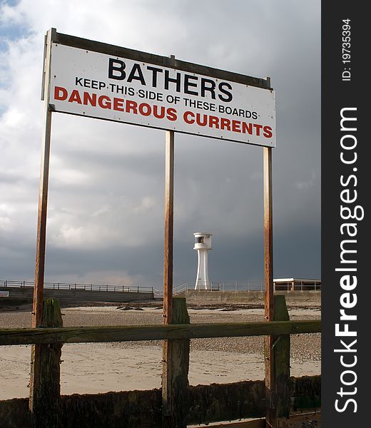 Warning sign on a beach and lighthouse