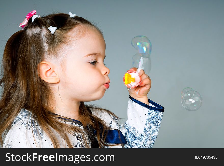 Cute little girl playing with bubbles in the studio. Cute little girl playing with bubbles in the studio