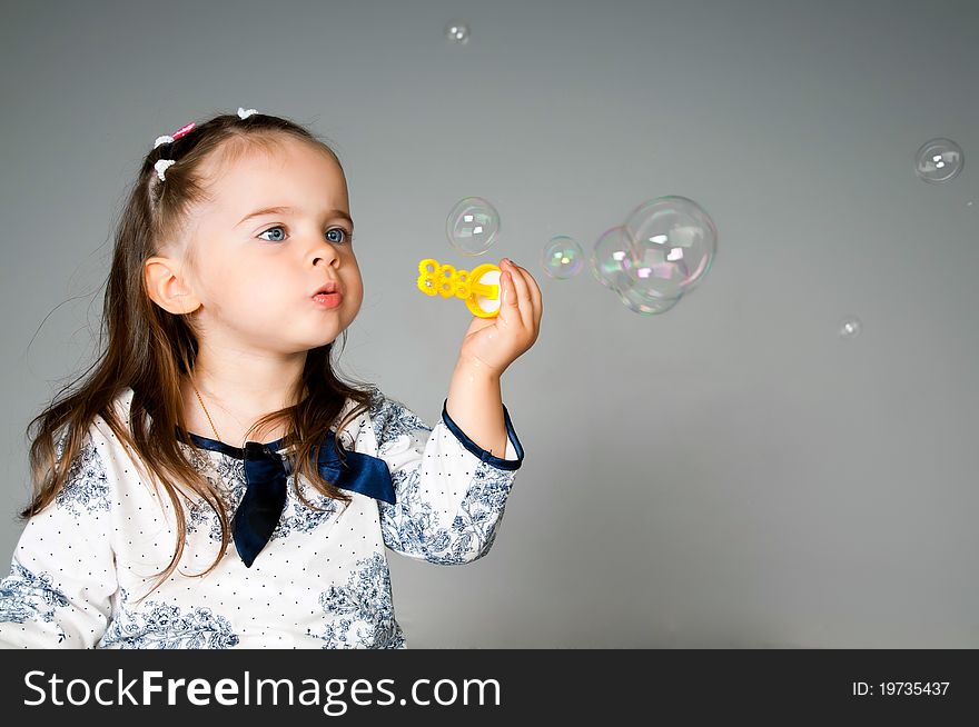 Cute little girl playing with bubbles in the studio. Cute little girl playing with bubbles in the studio