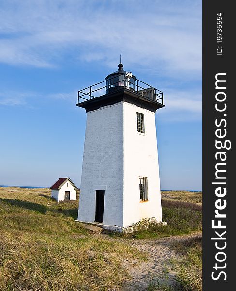 White old lighthouse with small house of its keeper