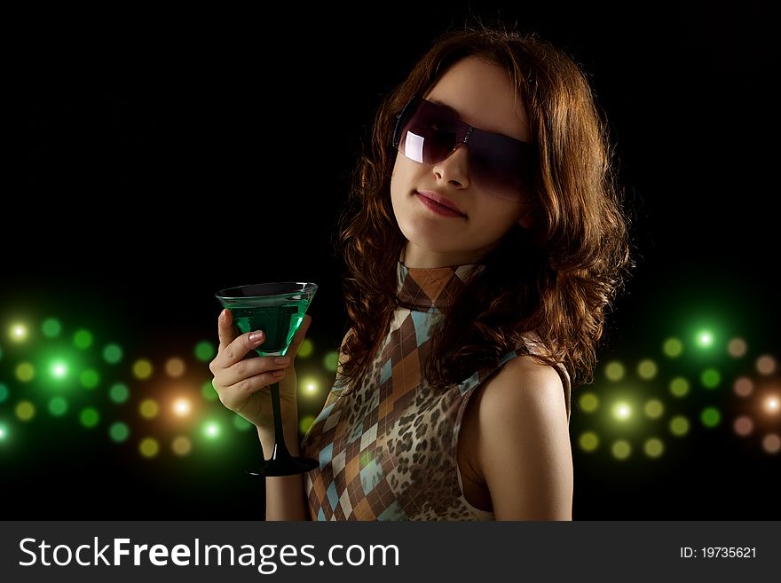 Young woman with a green cocktail on a black background