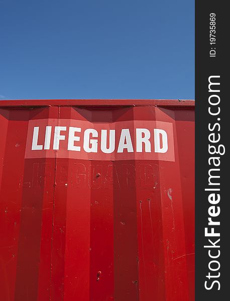 Lifeguard sign on red house with blue sky