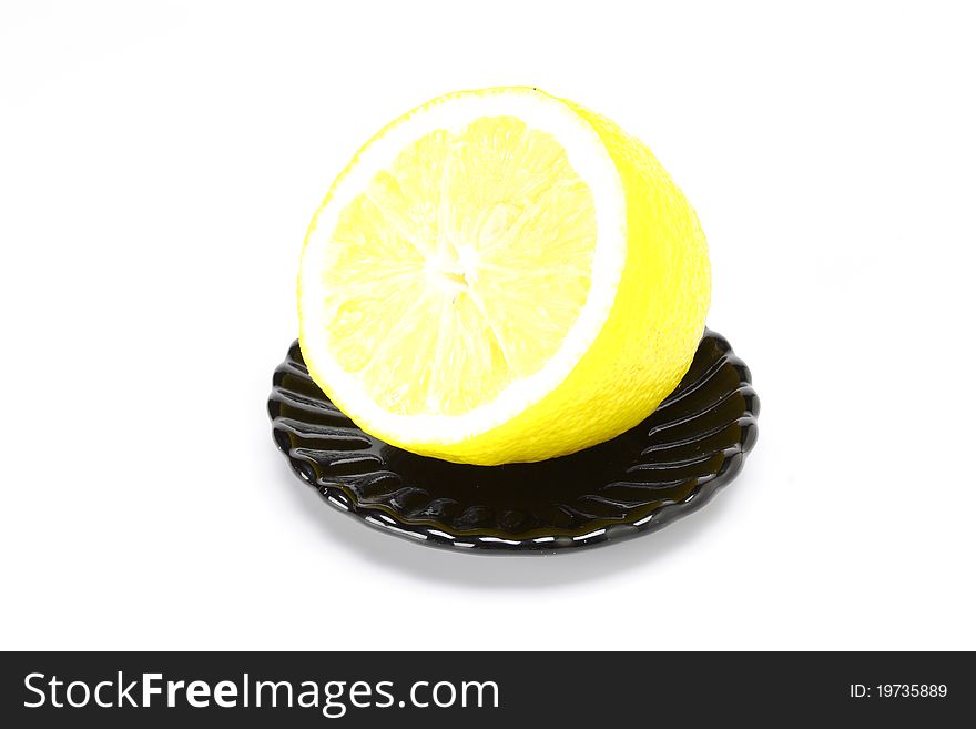 Lemon on black plate on a white background. Lemon on black plate on a white background