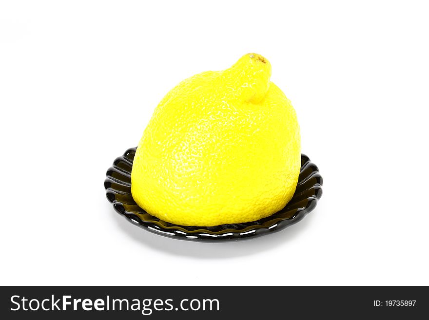 Lemon on black plate on a white background. Lemon on black plate on a white background