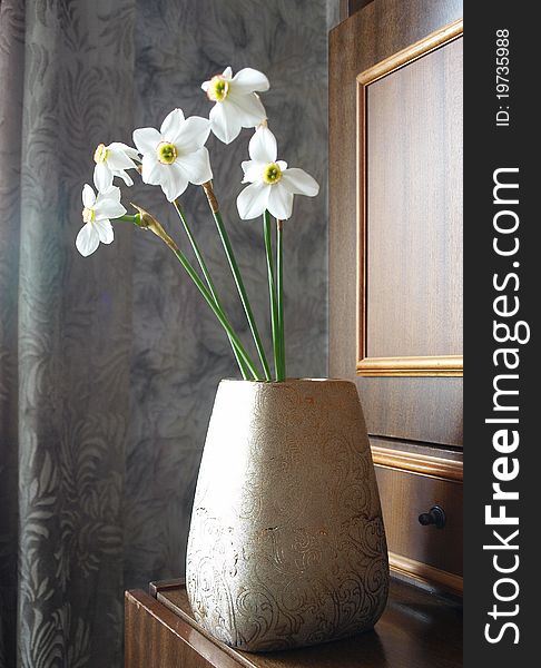 A vase of white daffodils against an grey interior