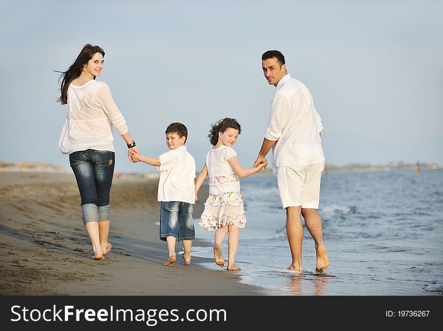 Happy Young Family Have Fun On Beach At Sunset