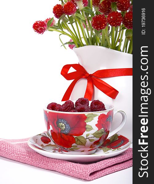 Raspberry in a beautiful cup and a bunch of flowers on a white background. Raspberry in a beautiful cup and a bunch of flowers on a white background