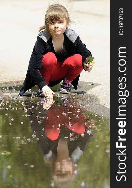 Young girl playing with puddle in spring season. Young girl playing with puddle in spring season