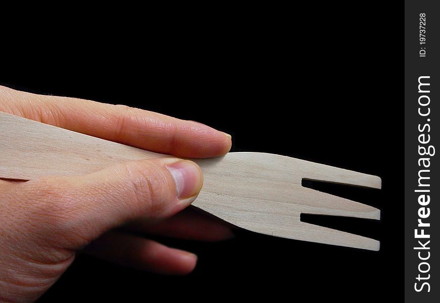 Person holding a wooden spatula, isolated towards black background