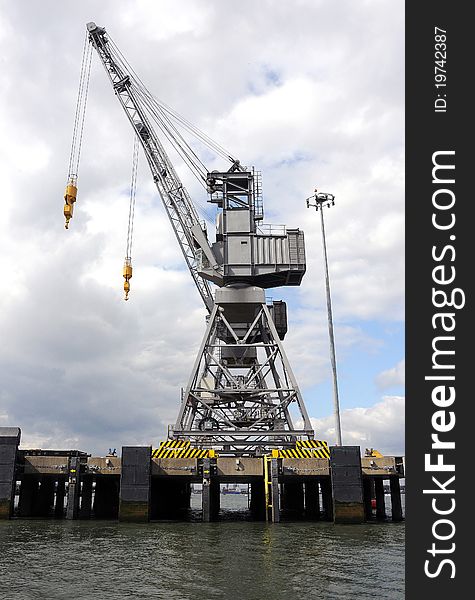 A grey dockyard crane against a cloudy sky