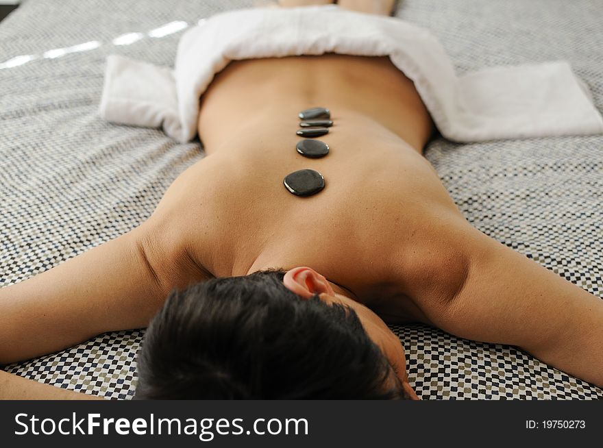 Woman getting hot stone massage with black pebbles