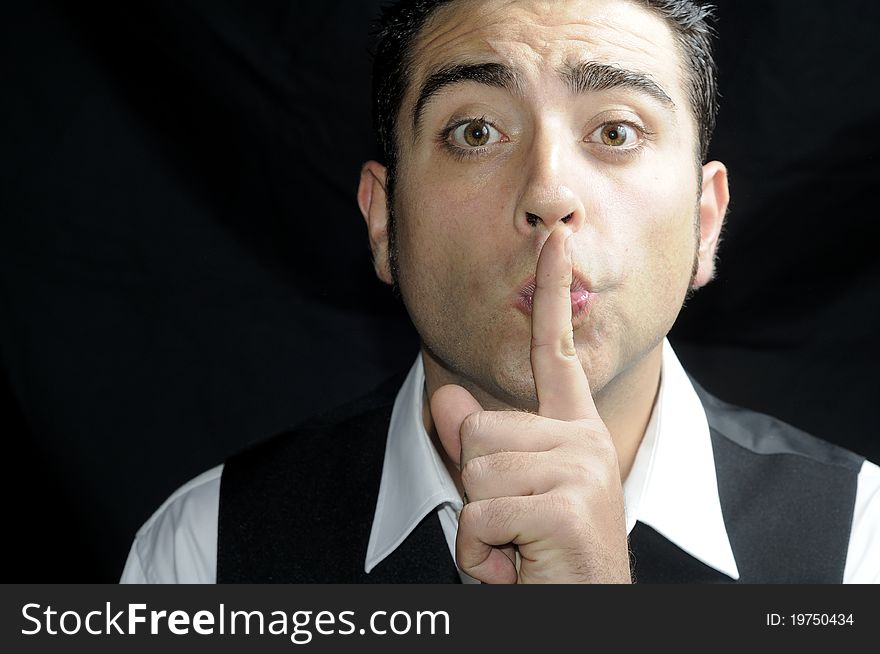 Portrait of a man with a finger in his lips on black background