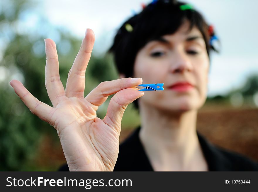 Funny image, using the shallow depth of field to focus attention on the hand of the model, which contains a clothespin. Ironic symbol of consumerism. Funny image, using the shallow depth of field to focus attention on the hand of the model, which contains a clothespin. Ironic symbol of consumerism.