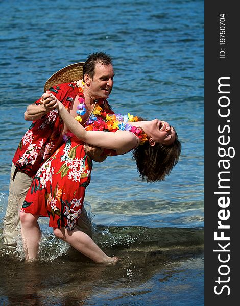 An excited couple on vacation dance in the waves on a beach in Maui, Hawaii. An excited couple on vacation dance in the waves on a beach in Maui, Hawaii.