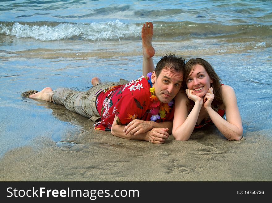 A couple vacationing in Hawaii allows the surf to wash over them as they lie on a beach in Lahaina, Maui. A couple vacationing in Hawaii allows the surf to wash over them as they lie on a beach in Lahaina, Maui.