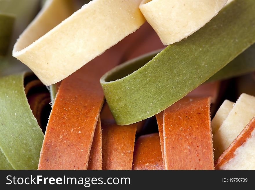 Dried colorful fettucine. Plain, tomato and spinach, in closeup. Dried colorful fettucine. Plain, tomato and spinach, in closeup.