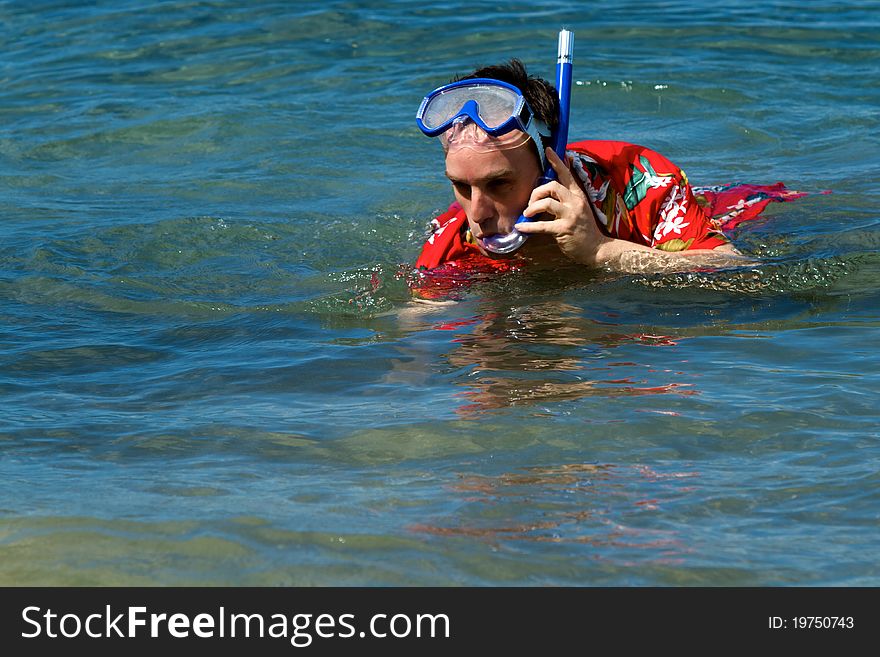 A man snorkels in his Hawaiian print shirt