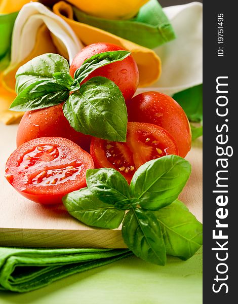 Photo of sliced cherry tomatoes with basil on wooden cutting board. Photo of sliced cherry tomatoes with basil on wooden cutting board