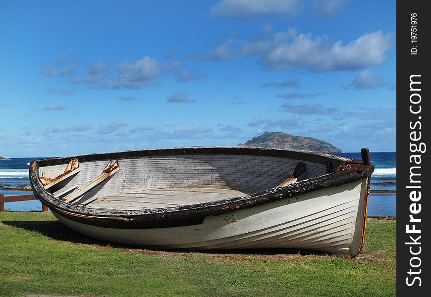 An old whaling boat on beach with blue sky and island background. An old whaling boat on beach with blue sky and island background