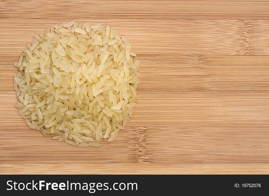 Pile of raw rice on wooden table, view from the top