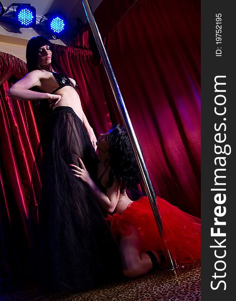 Two young attractive women in lingerie and high heels pole dancing in the adult entertainment club. Two young attractive women in lingerie and high heels pole dancing in the adult entertainment club