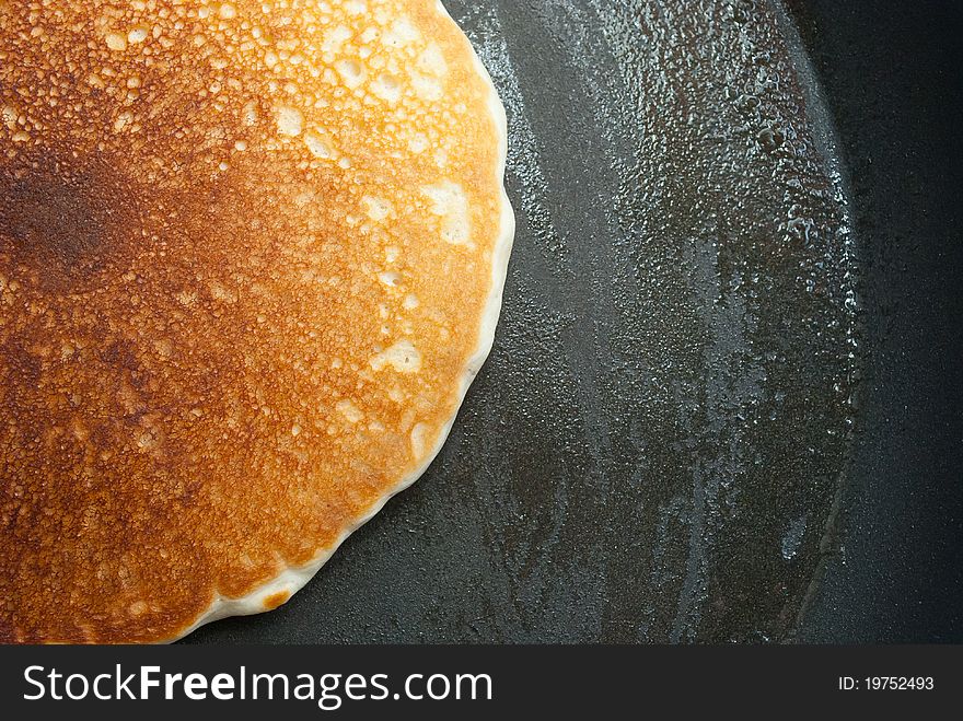 A pancake in a buttered frying pan. A pancake in a buttered frying pan.