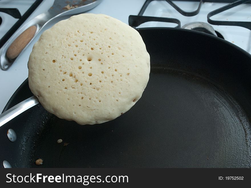 Pancake being flipped to cook on other side. Pancake being flipped to cook on other side.