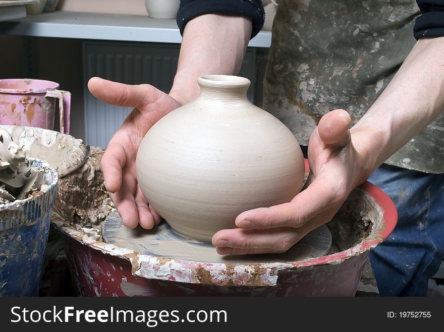The hands of a potter, creating an earthen jar on the circle, close-up