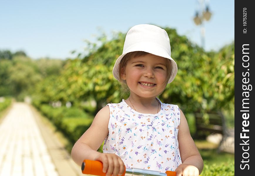 Little adorable girl posing with orange scooter in the park. Little adorable girl posing with orange scooter in the park