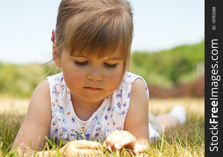 Little Girl Lying On Grass In The Park