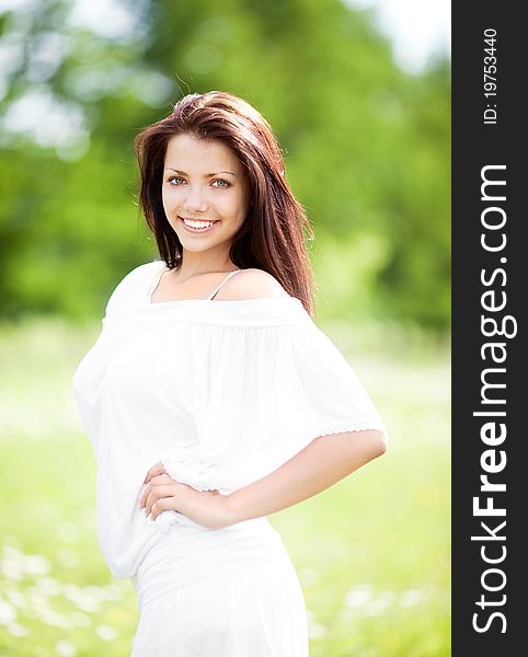 Beautiful young brunette woman  on the  meadow with white flowers  on a warm summer day. Beautiful young brunette woman  on the  meadow with white flowers  on a warm summer day