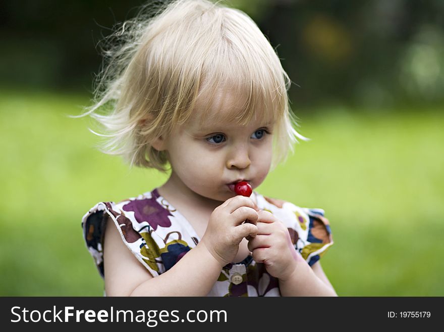 A portrait of a little girl holding a cherry