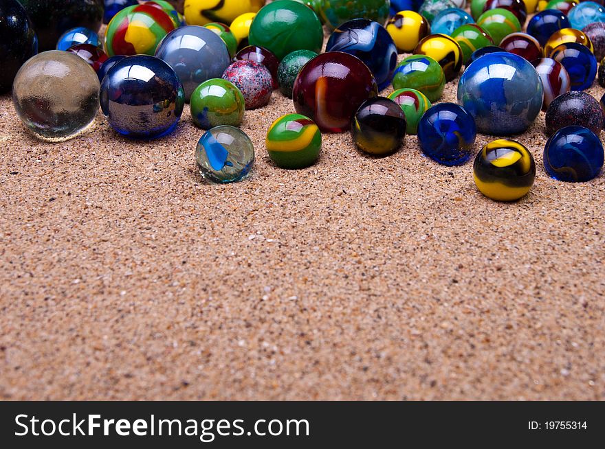 Colored glass marbles on a sandy background