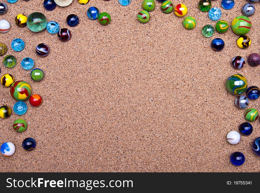 Colored glass marbles on a sandy background