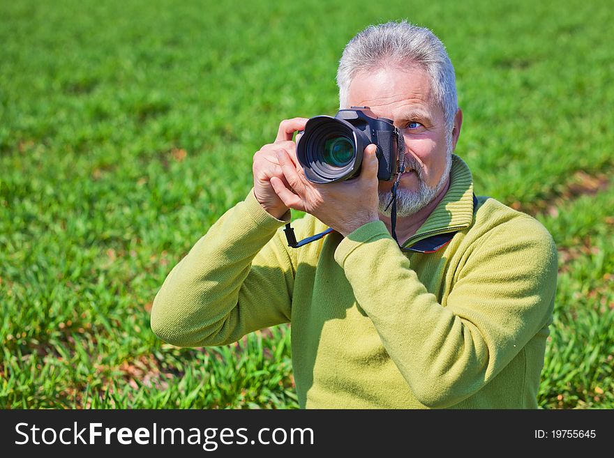Photographer on green field holding camera. Photographer on green field holding camera