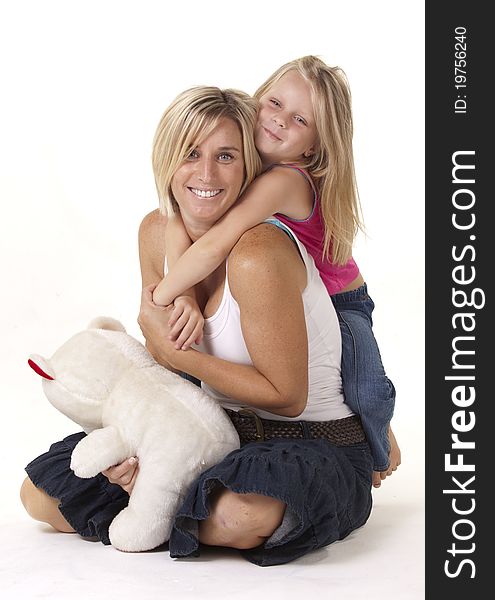 Attractive blonde mother and daughter, in a loving embrace, with a teddy bear. Attractive blonde mother and daughter, in a loving embrace, with a teddy bear.