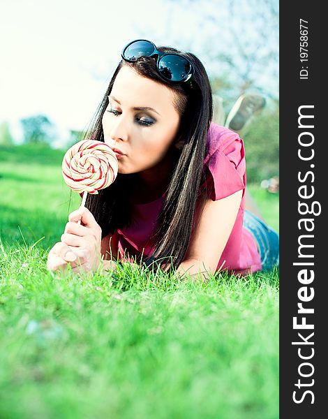 Beautiful girl and great candy. Relax on the green grass. Beautiful girl and great candy. Relax on the green grass