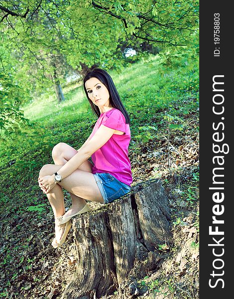 Elegant woman sitting on a stump