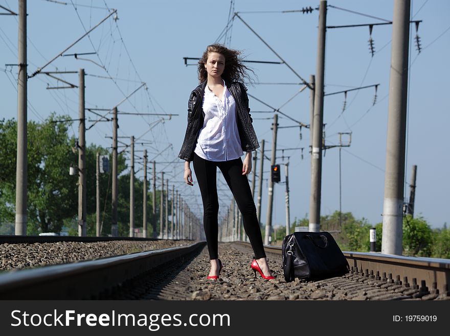 A girl sits on the rail waiting for the train. A girl sits on the rail waiting for the train