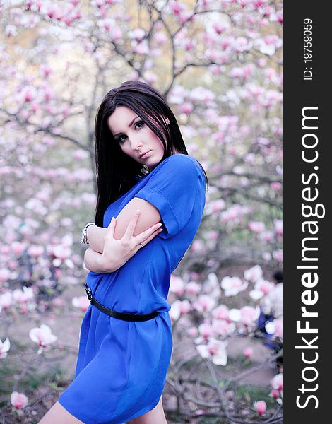 A girl in a blue dress in the garden of magnolias