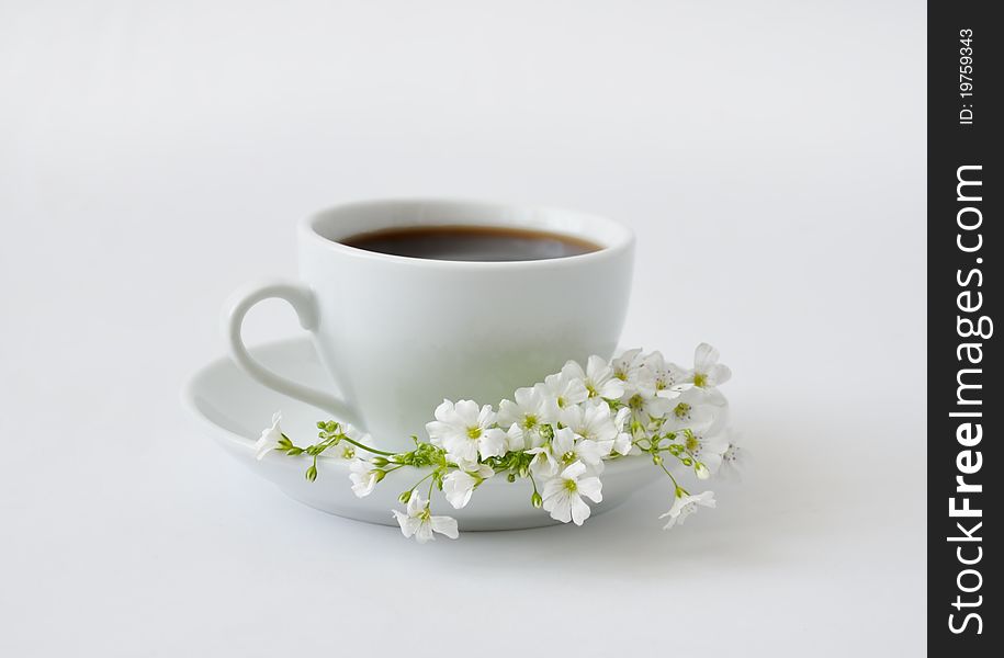 A cup of black coffee with flowers on a gray background